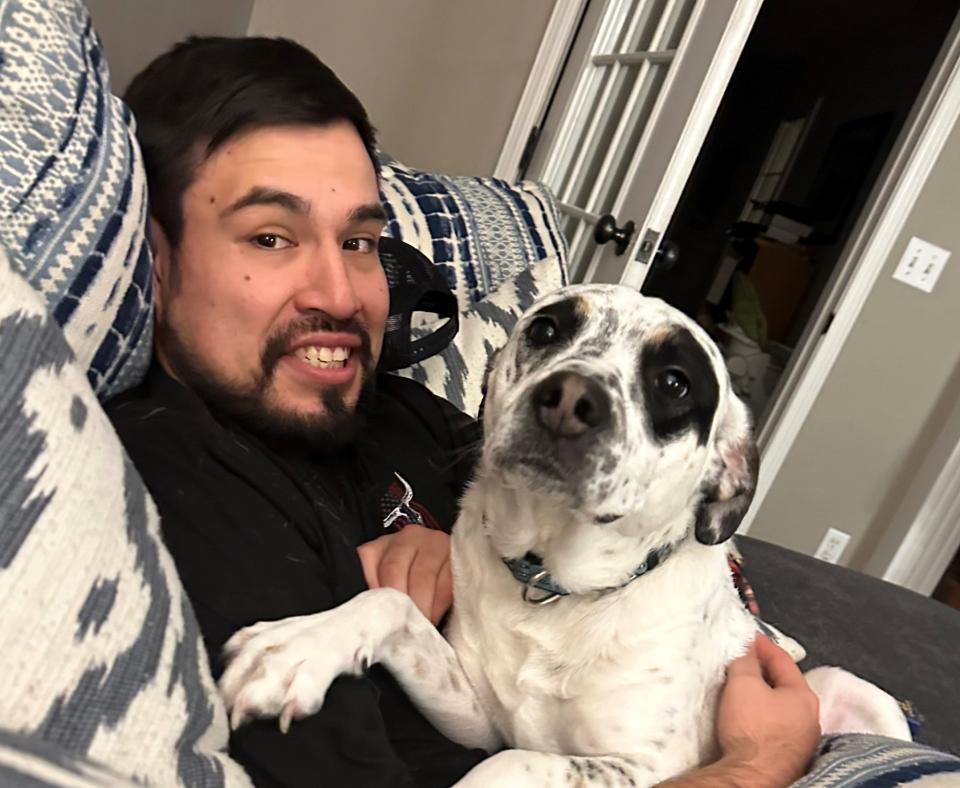 Neo the dog snuggling with a smiling person on a couch